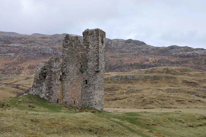 Close view of Ardvreck Castle tower ruins with rugged hills behind