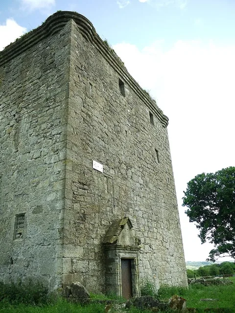 Barr Castle viewed from below at a corner, with its doorway and stone parapet visible.