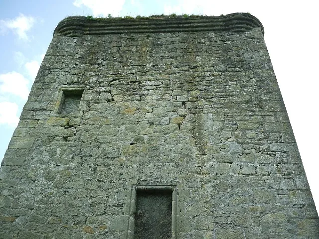Upward view of a weathered Barr Castle wall with blocked windows beneath the parapet.