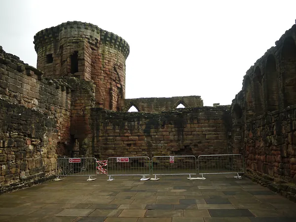 Roofless stone interior and round tower at Bothwell Castle with temporary barriers