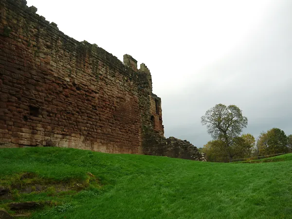 Long sandstone wall of Bothwell Castle above the grass