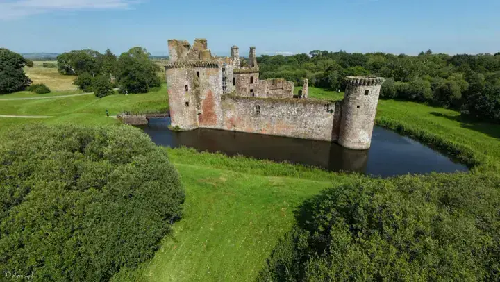 Elevated view of Caerlaverock Castle, its moat and surrounding lawns
