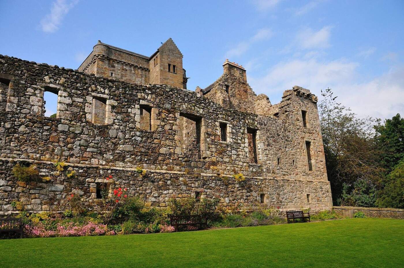 Castle Campbell stone ruins above flower beds and a lawn