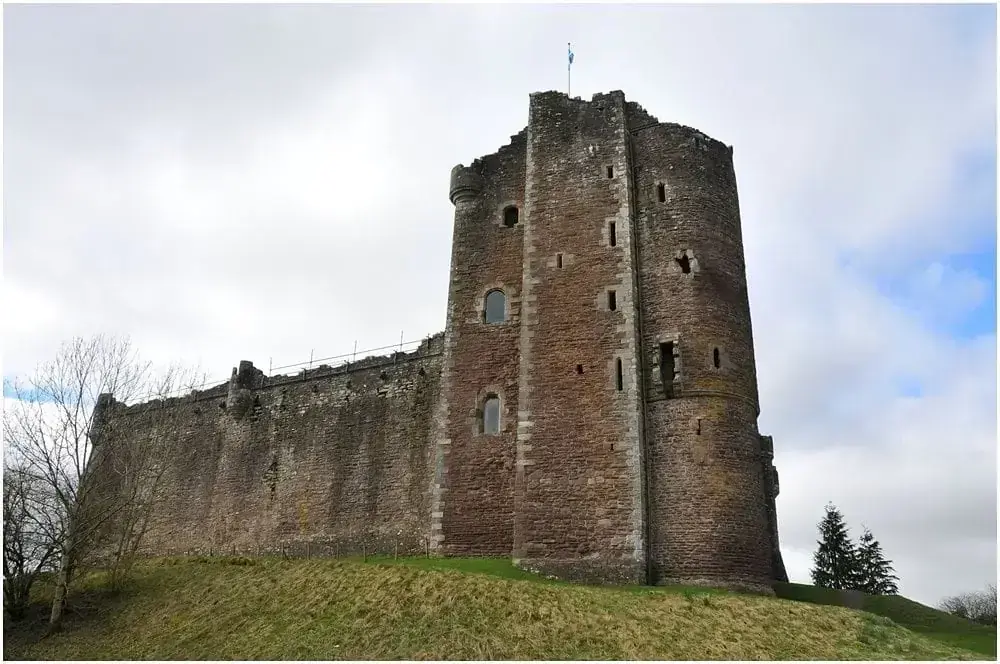 Doune Castle’s stone tower and wall seen from a grassy slope