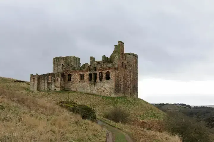 Crichton Castle ruins seen across a dry grassy hillside
