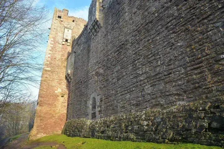 Doune Castle's high curtain wall viewed from the narrow strip of lawn below