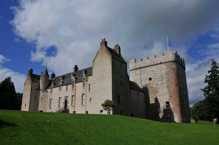 Drum Castle wing and stone tower above a sunlit lawn