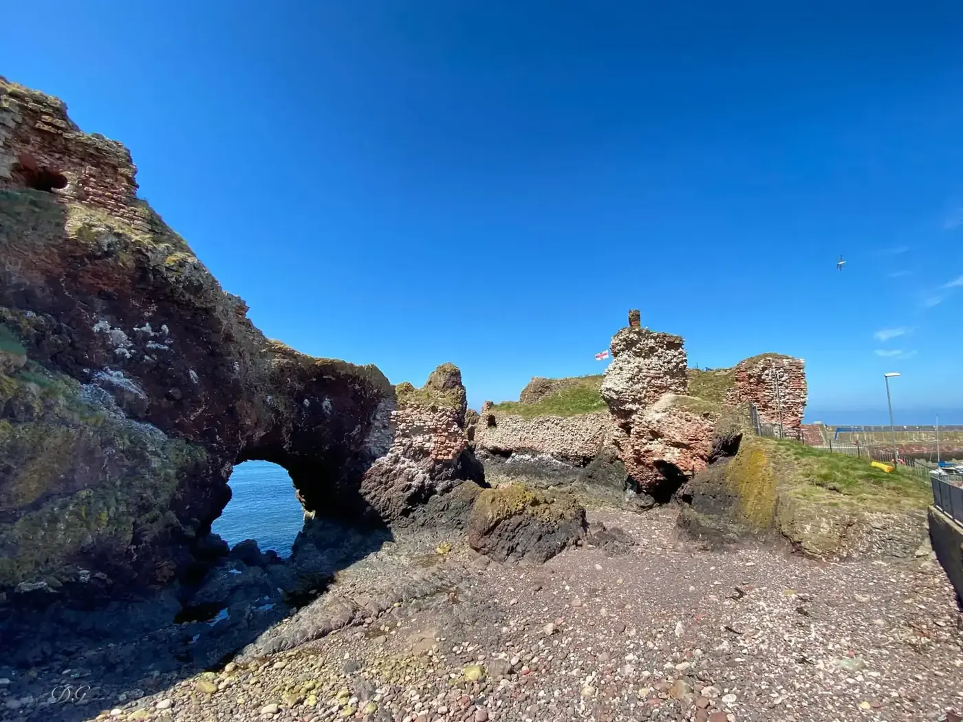 Dunbar Castle ruins and a rock arch above an exposed shoreline