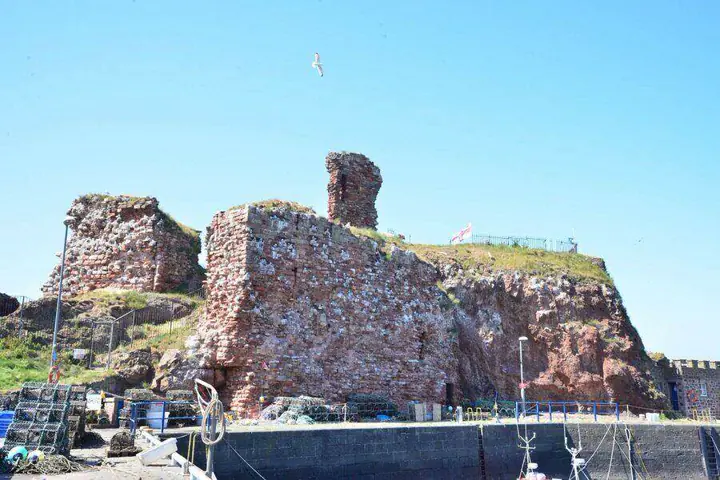 Dunbar Castle ruins rising above harbour walls and boat masts