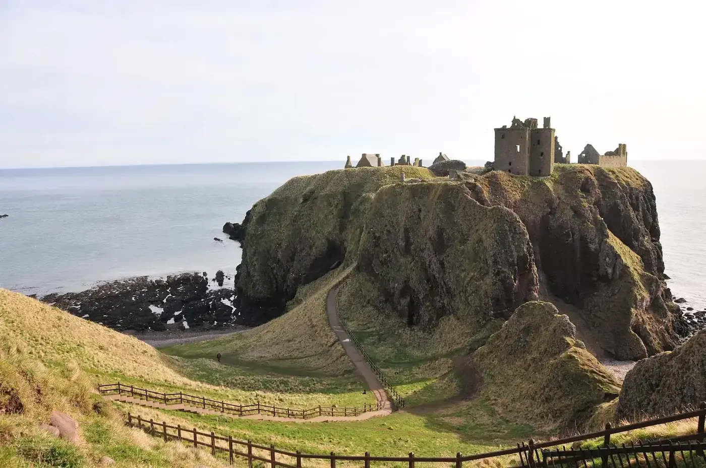 Dunnottar Castle on a steep coastal promontory with a fenced path below