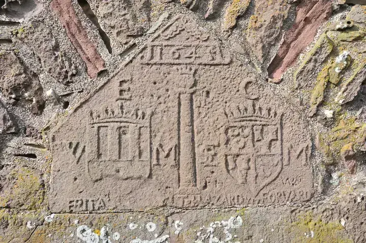 Weathered carved stone panel with heraldic shields at Dunnottar Castle