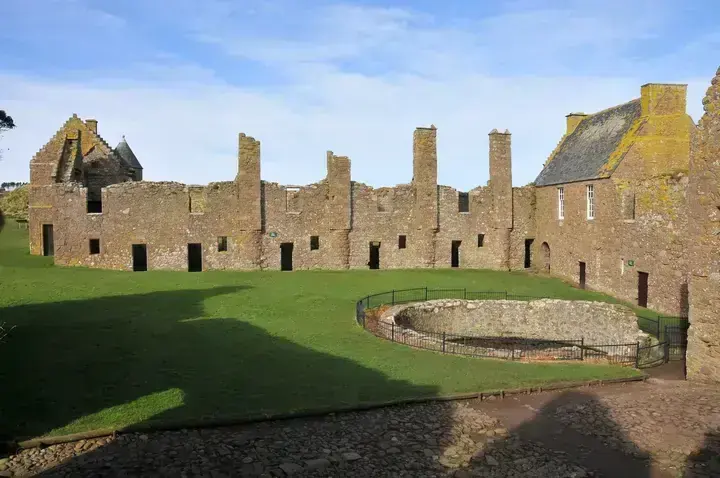 Dunnottar Castle courtyard lawn surrounded by stone walls and tall chimneys