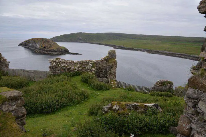 Duntulm Castle wall remnants above a sheltered bay and green headland