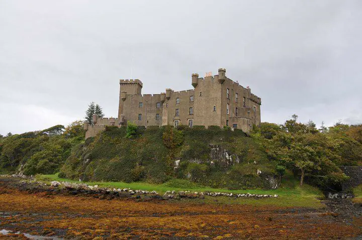 Dunvegan Castle on a rocky rise above a seaweed-covered shore