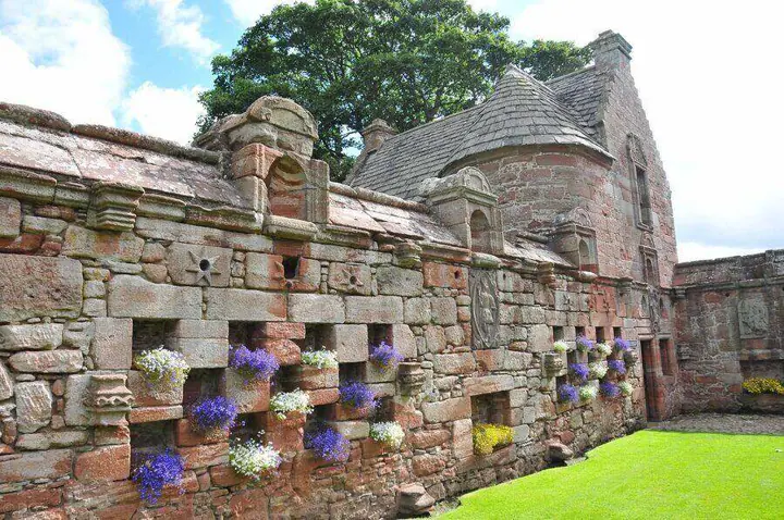 Carved garden wall with flowering niches and a small gabled building at Edzell Castle