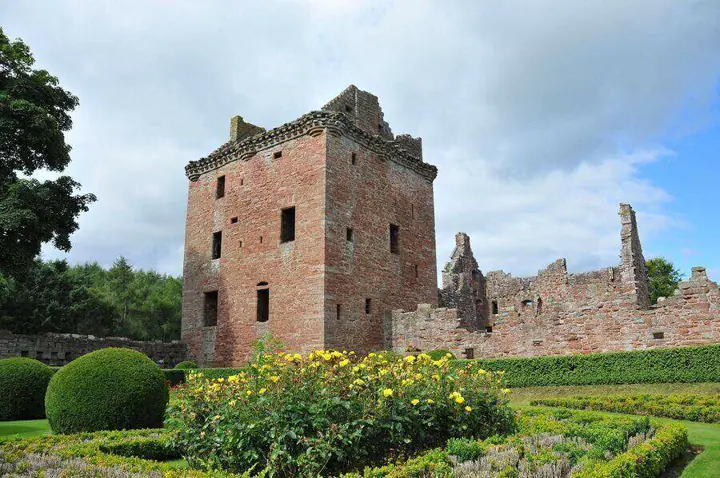 Edzell Castle's red stone tower behind yellow flowers and clipped shrubs