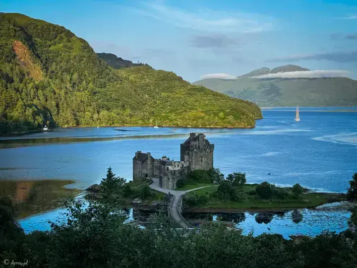 Elevated view of Eilean Donan Castle and bridge beside wooded hills