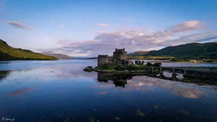 Eilean Donan Castle reflected in calm water under pink evening clouds