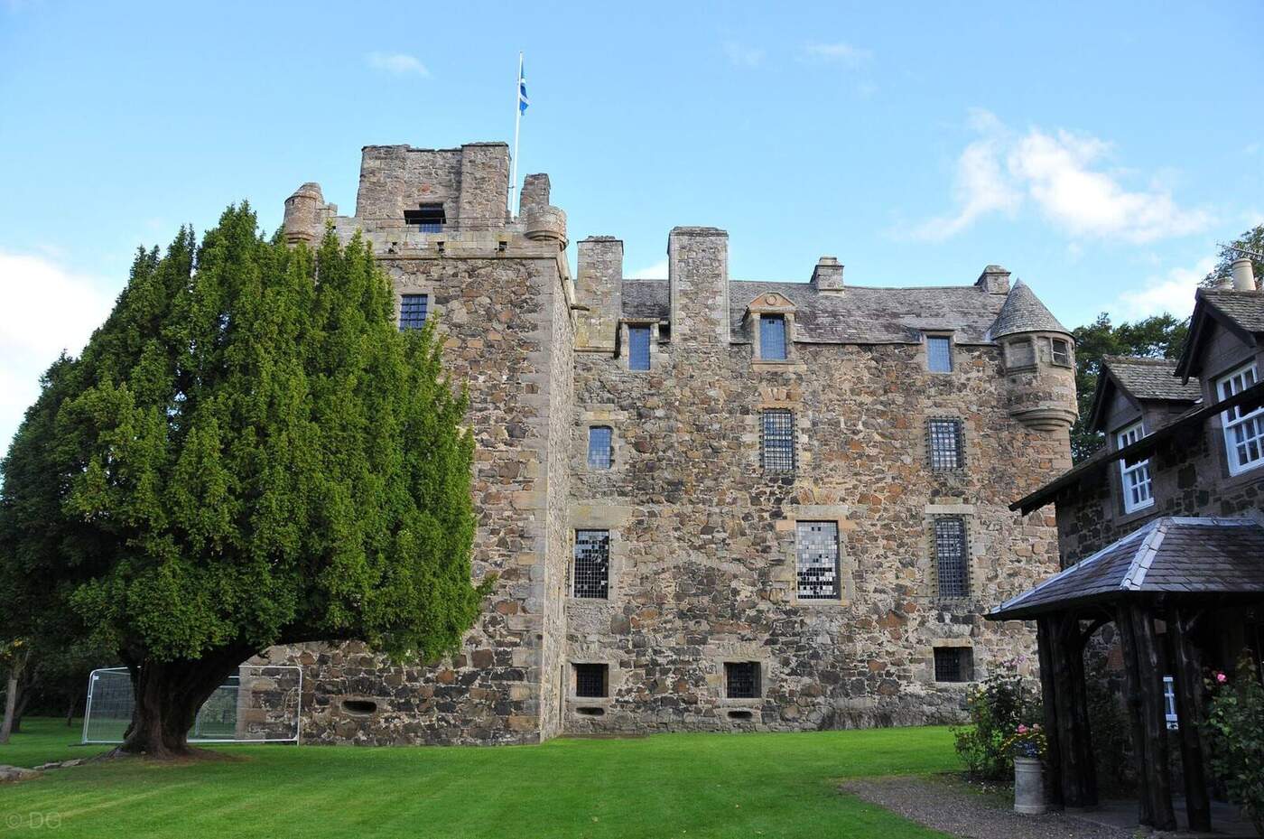 Elcho Castle stone facade and corner turrets beside mature trees