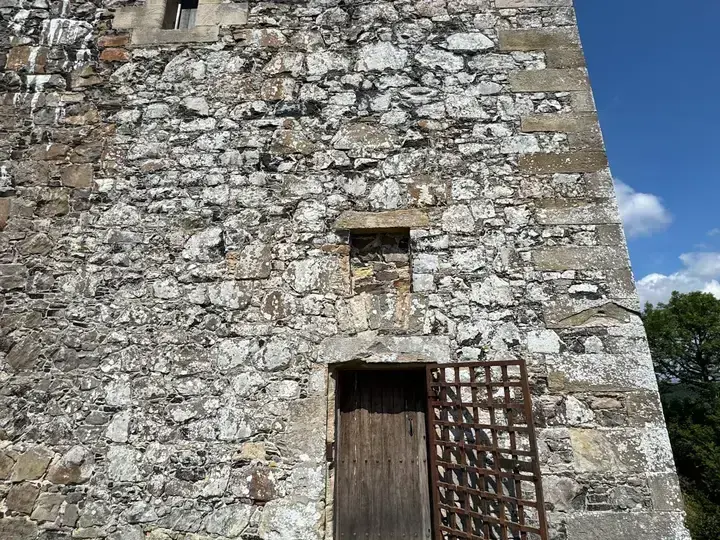 Stone doorway at Fatlips Castle with a wooden door and metal grille