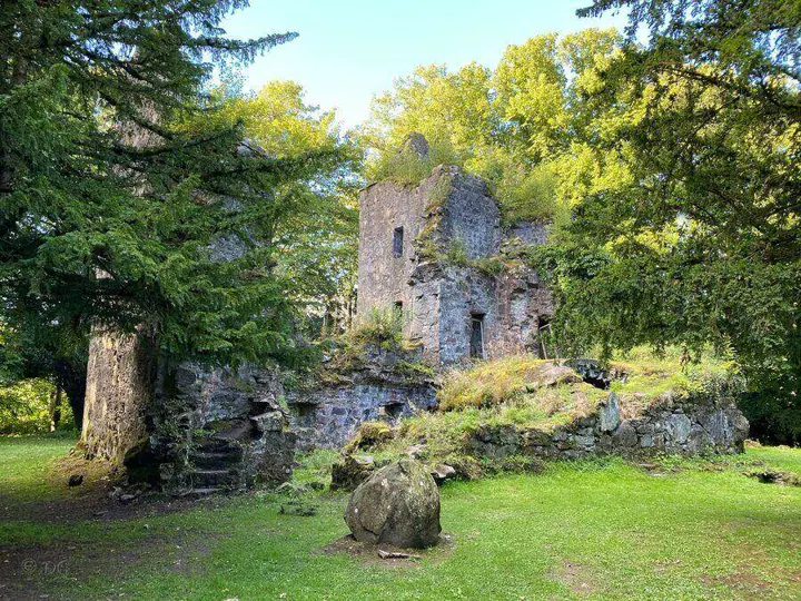 Finlarig Castle ruins beyond a grassy clearing and large rock