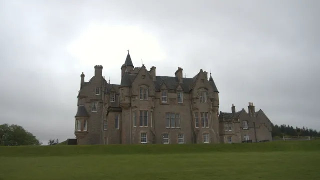Wide view of Glengorm Castle across its green grounds beneath grey clouds