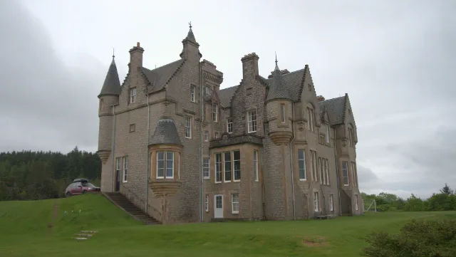 Glengorm Castle stone walls with projecting turrets beneath cloudy skies