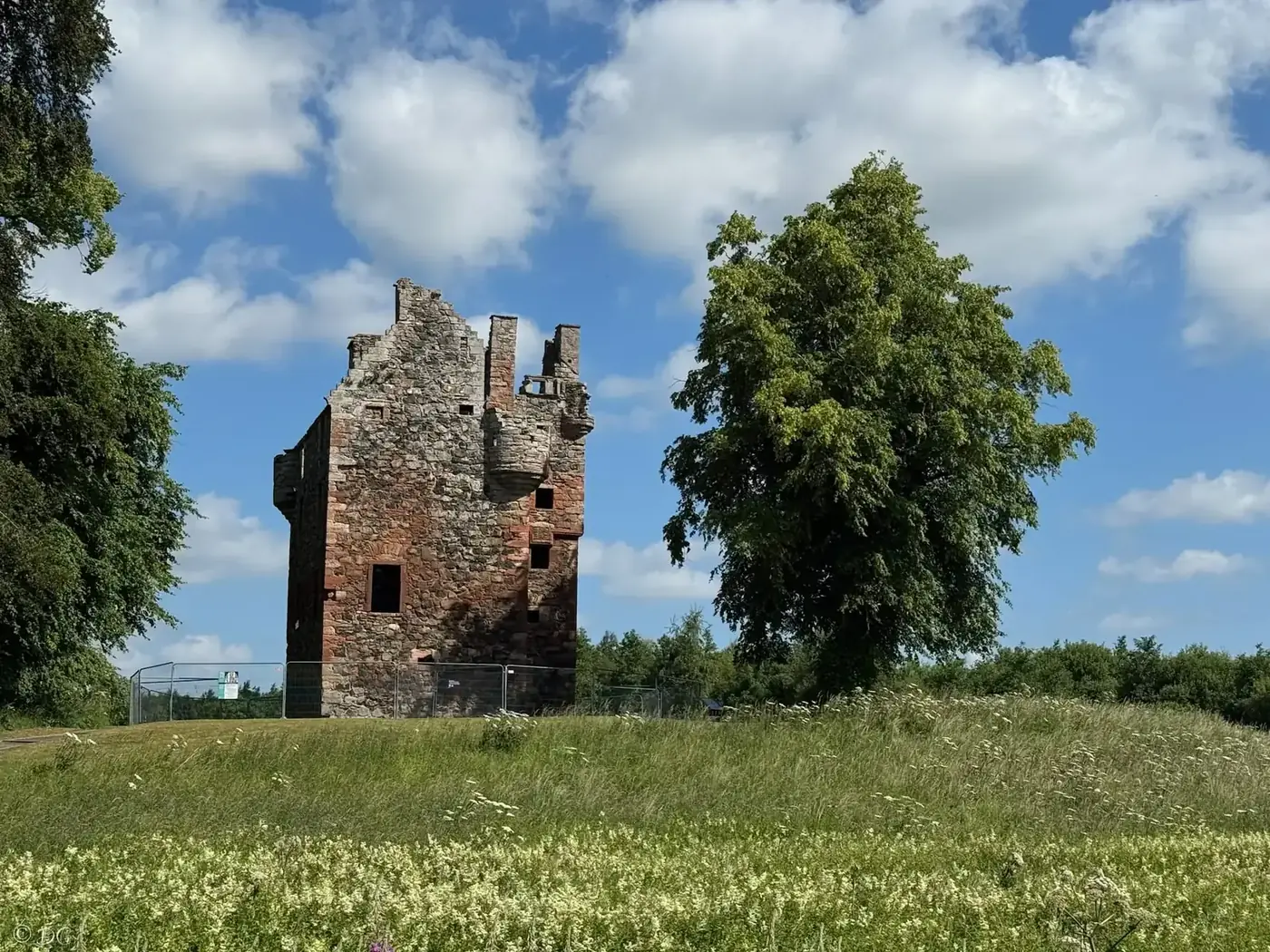 Greenknowe Tower wall with red stone window surrounds and a turret