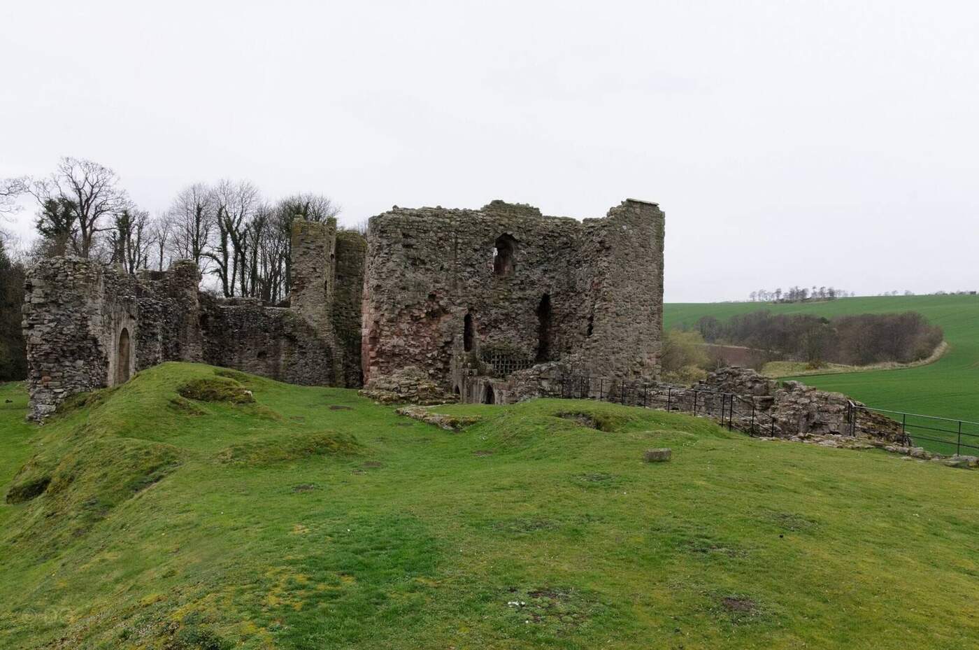 Hailes Castle ruins above a grassy bank with farmland beyond