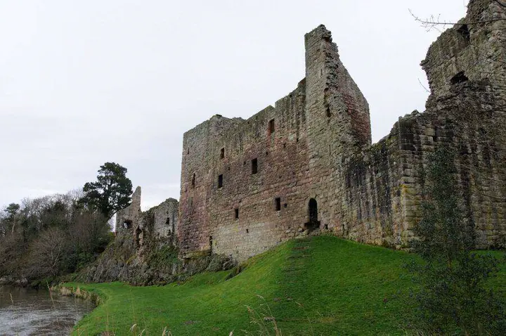 Hailes Castle's long roofless facade viewed from beside the river