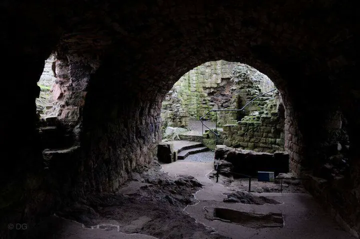 View through a dark vaulted passage to stone steps at Hailes Castle