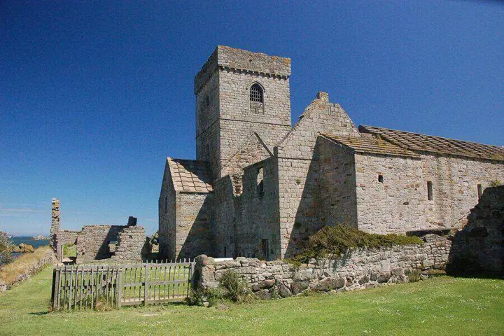 Inchcolm Abbey's square tower and gabled stone walls beyond a wooden gate