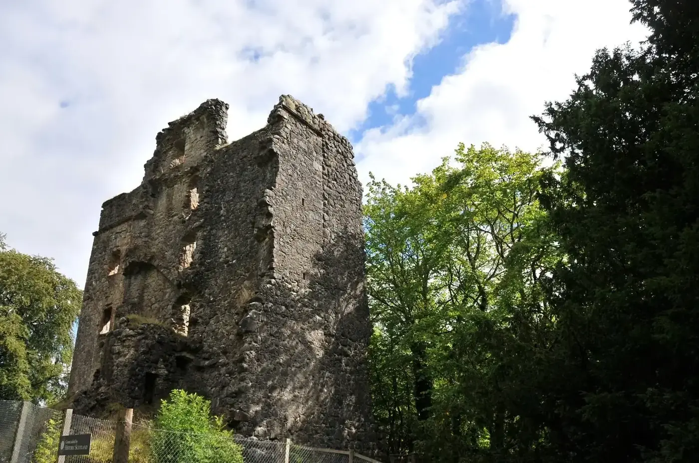 Invergarry Castle roofless tower among trees behind a fence