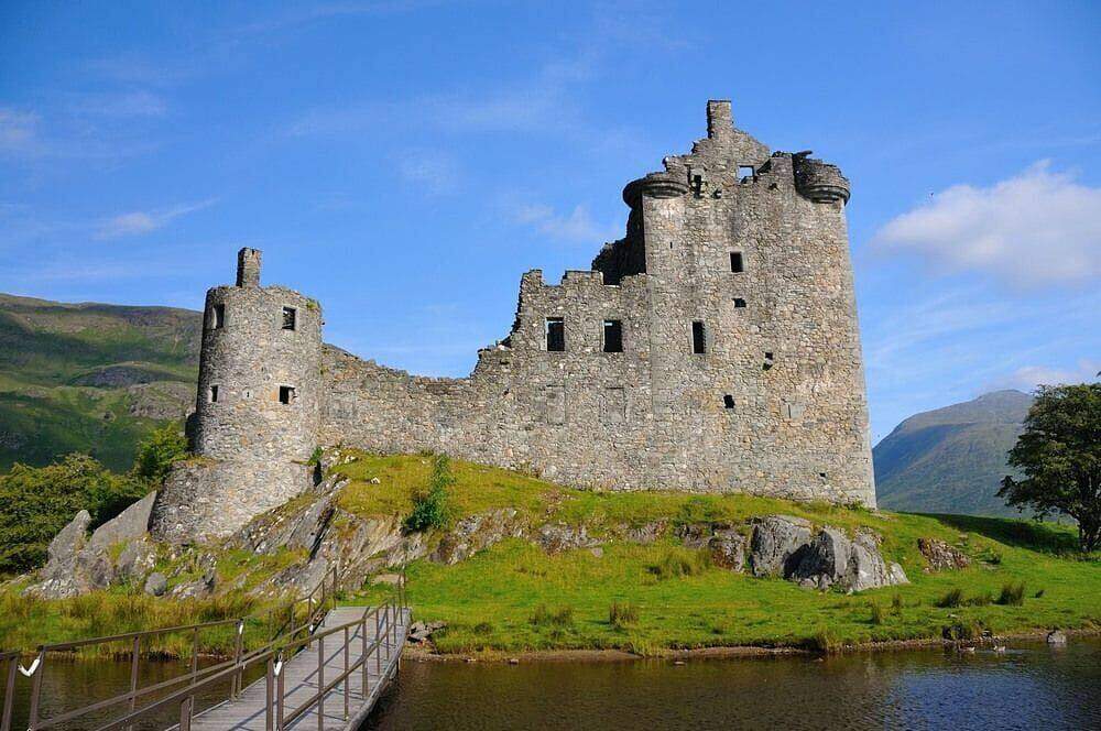 Kilchurn Castle above the water beside a footbridge