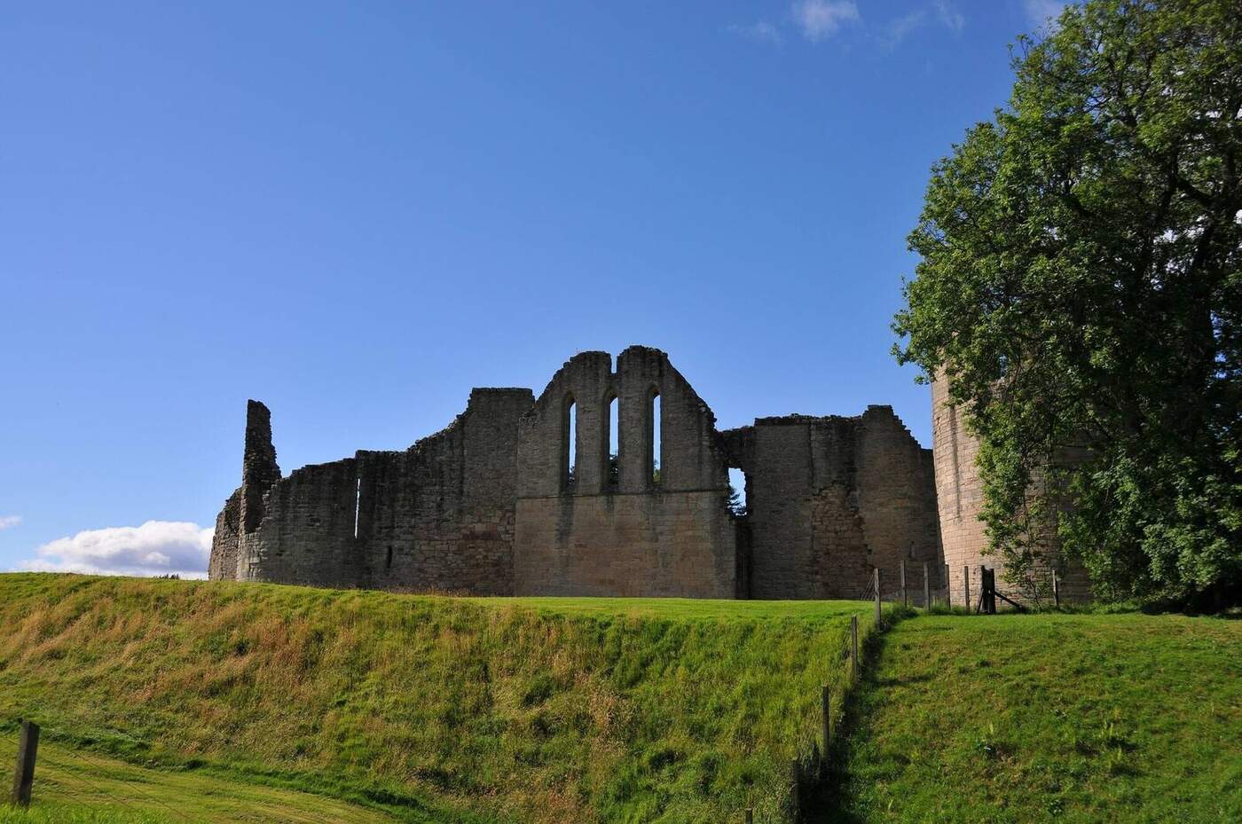 Kildrummy Castle's roofless walls and tall window openings above a grassy bank