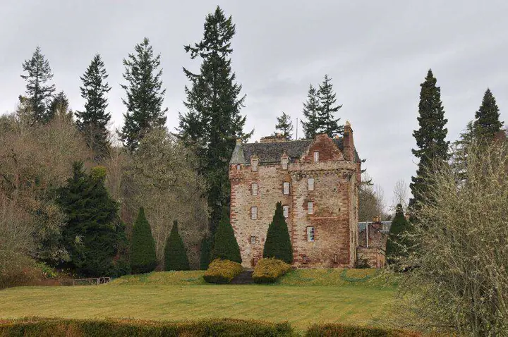 Castle Leod framed by tall trees and clipped conifers