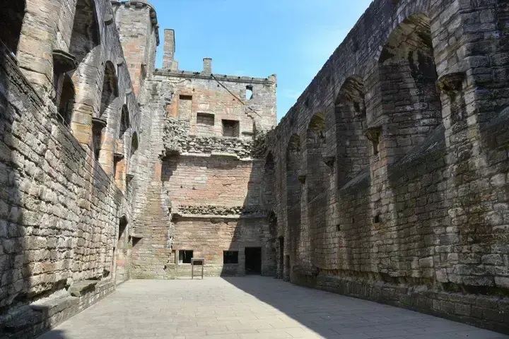 Roofless interior of Linlithgow Palace with a row of arched recesses