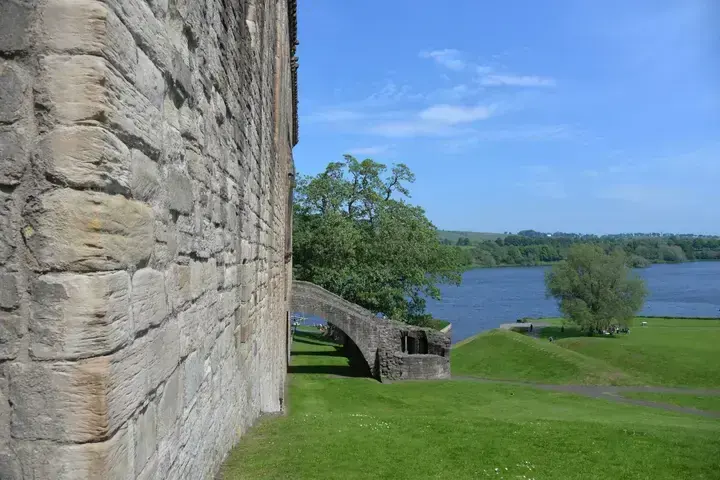 Linlithgow Palace outer wall beside green lawns and the loch