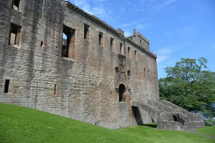 Long stone façade of Linlithgow Palace above a grassy slope