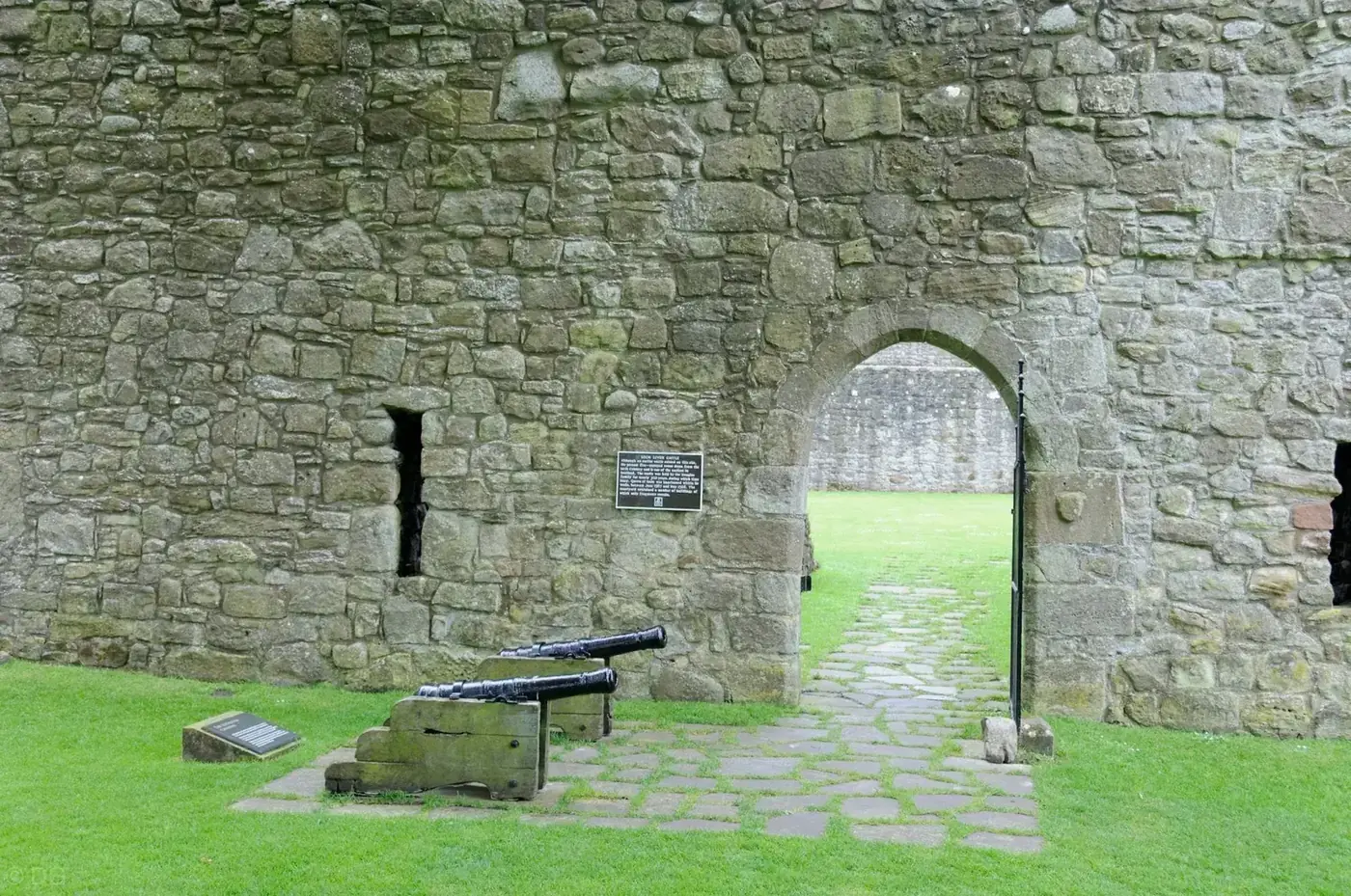 Cannon beside an arched doorway in the walls of Loch Leven Castle