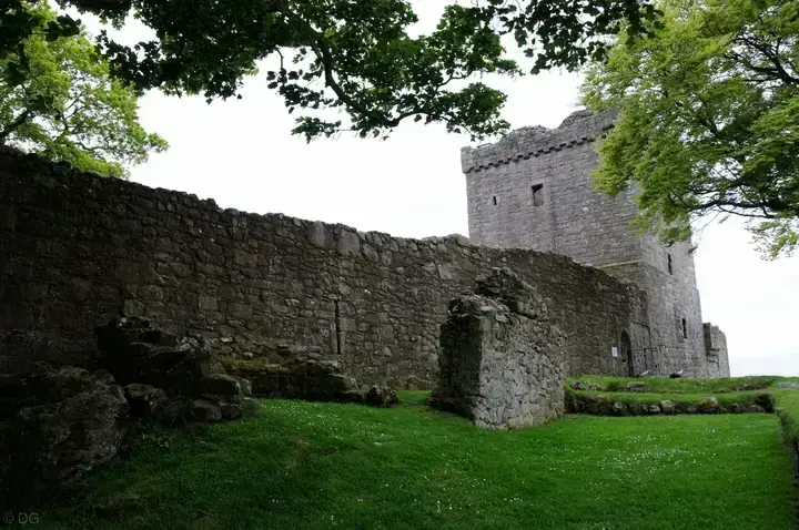Loch Leven Castle courtyard ruins and tower beneath tree branches