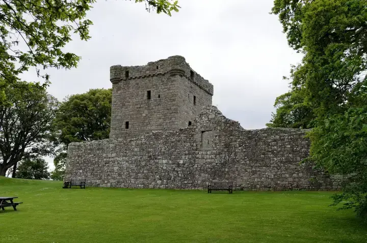 Loch Leven Castle tower behind its outer wall and green lawn