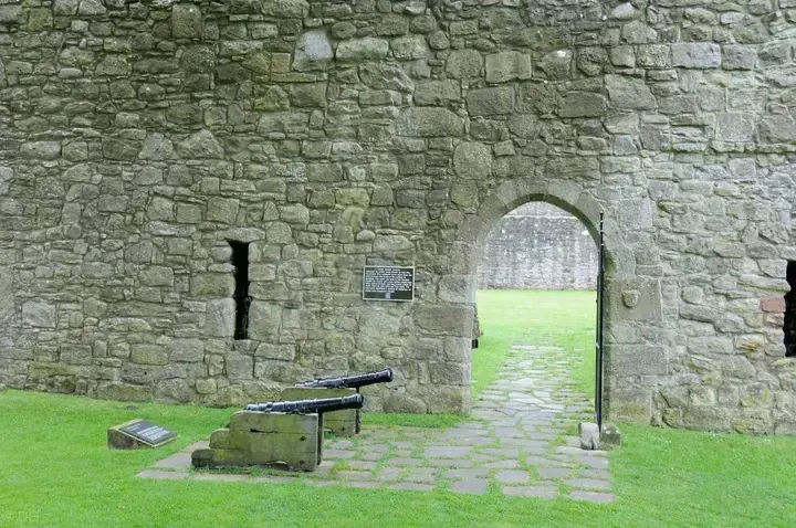 Cannon beside an arched doorway in the walls of Loch Leven Castle