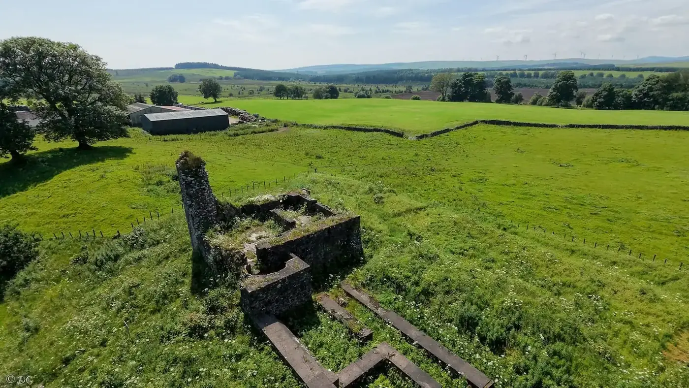 Aerial view of Lochwood Castle ruins among green fields