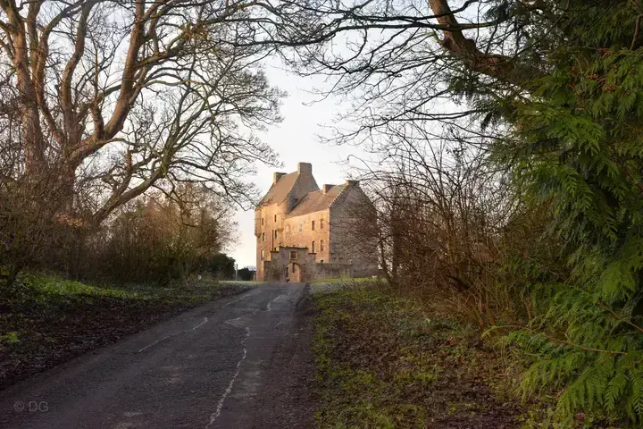 Midhope Castle at the end of a shaded lane between trees