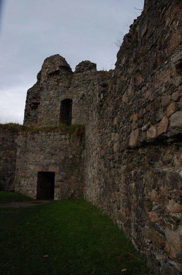 Stone wall and two dark openings inside Old Inverlochy Castle