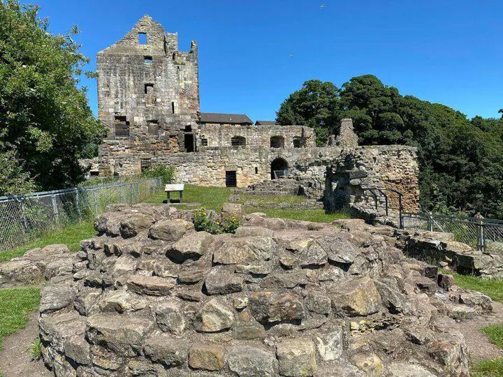 Low stone foundations before Ravenscraig Castle's ruined tower