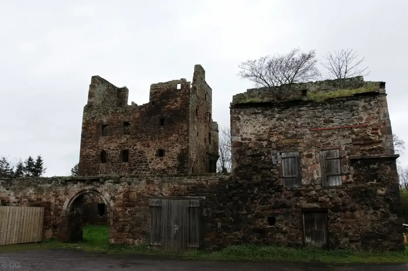 Redhouse Castle's ruined tower behind an arched gateway and low stone building
