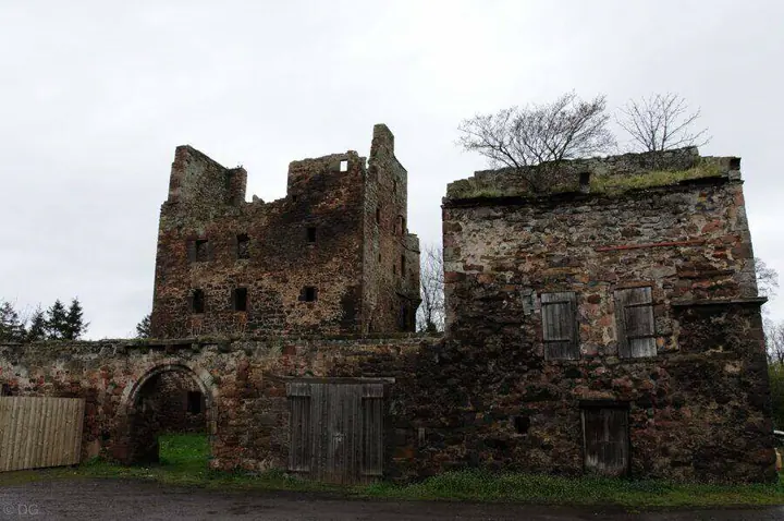 Redhouse Castle's ruined tower behind an arched gateway and low stone building