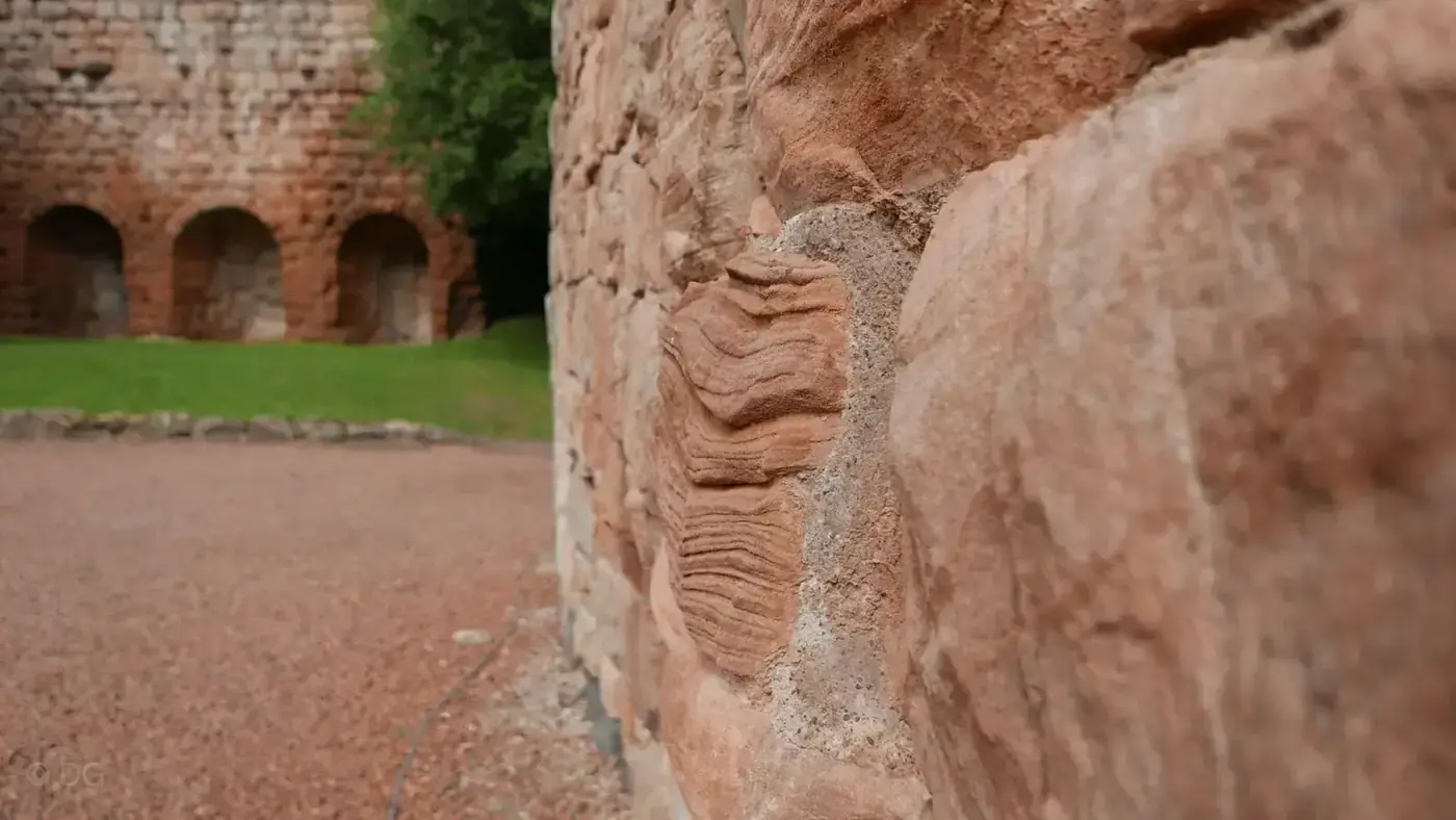 Close view of Roslin Castle's sandstone masonry with arched recesses beyond
